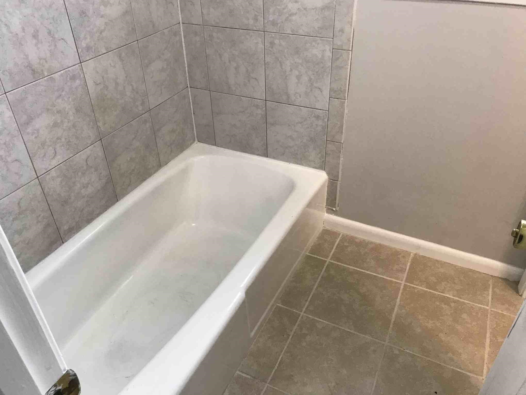 4502 Cottonwood Road Memphis, TN 38118 - Photo 13 of 16 White bathtub with light gray wall tiling and tan floor tiling