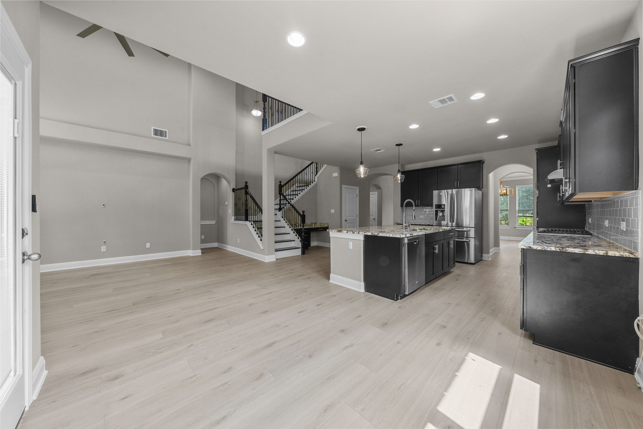 4401 Trinity Woods Street Leander, TX 78641 - Photo 12 of 37 A spacious layout showcases a gourmet kitchen island with bar seating, complemented by a grand staircase leading to the upper level.
