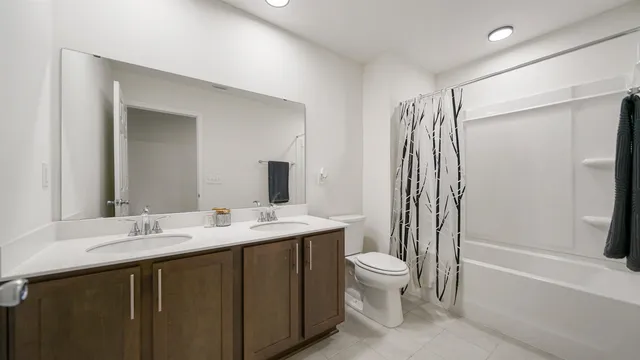 a bathroom with a double vanity sink toilet mirror and shower