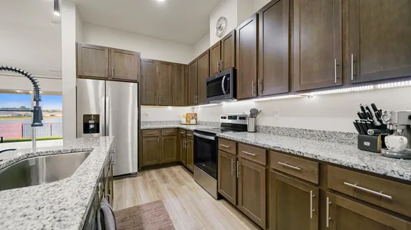 a kitchen with granite countertop stainless steel appliances a sink a stove and cabinets