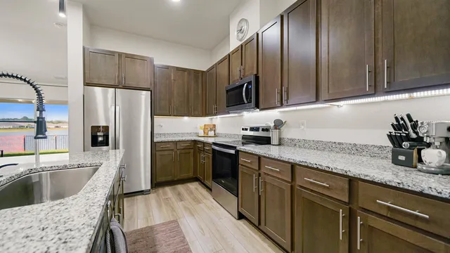 a kitchen with granite countertop stainless steel appliances a sink a stove and cabinets
