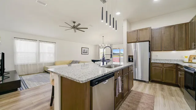 a kitchen with stainless steel appliances granite countertop a kitchen island a stove a refrigerator a sink and dishwasher