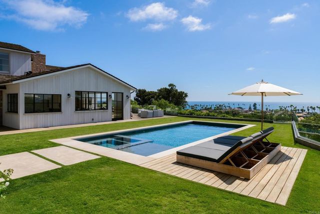 a view of swimming pool with lawn chairs under an umbrella