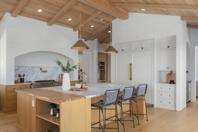 a kitchen with stainless steel appliances kitchen island granite countertop a table chairs and a refrigerator