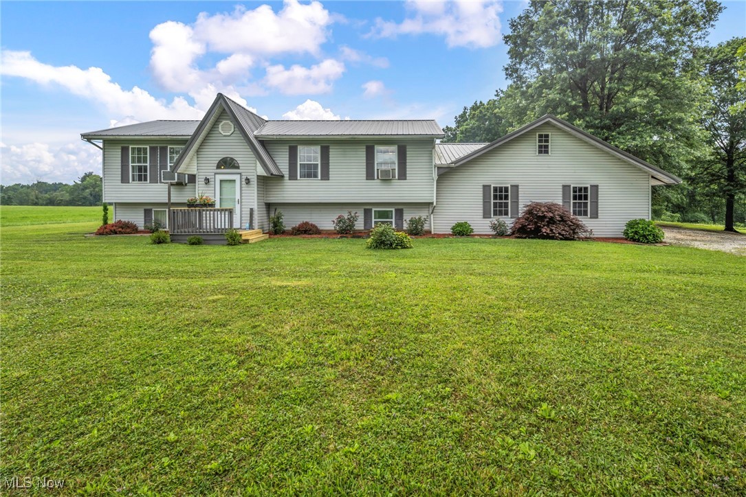 Bi-level home with a metal roof and a front lawn