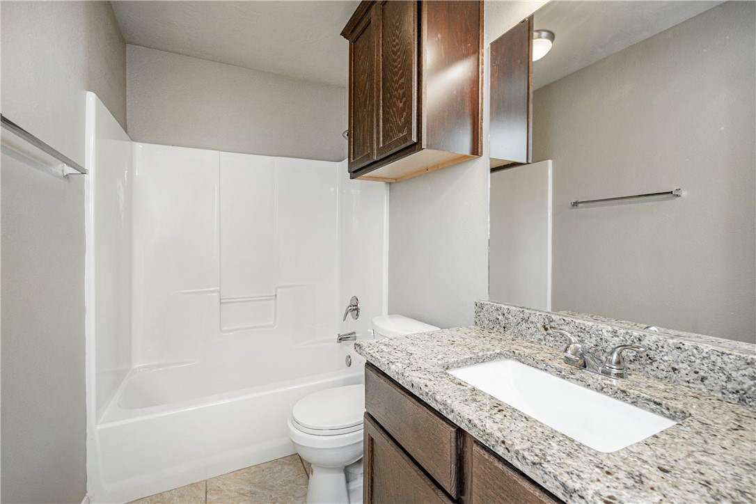 3009 Positano Loop Bryan, TX 77808 - Photo 18 of 21 a bathroom with a granite countertop sink a toilet and bathtub