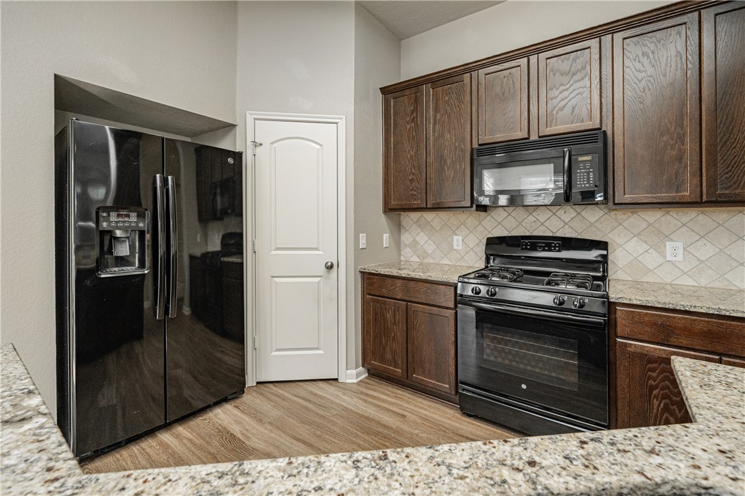 3009 Positano Loop Bryan, TX 77808 - Photo 10 of 21 a kitchen with granite countertop a refrigerator stove and microwave