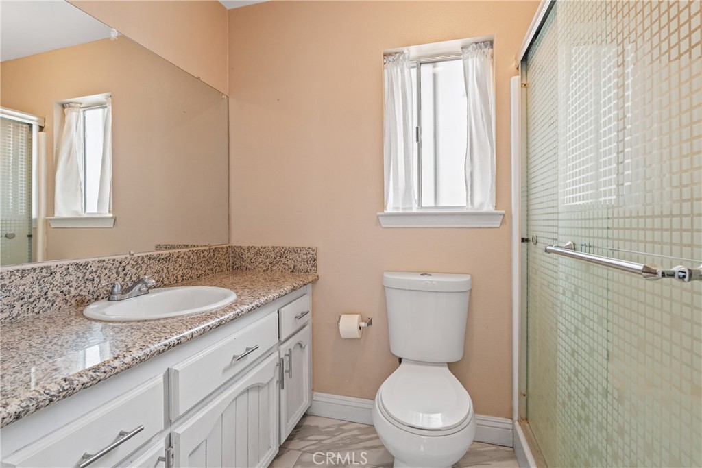 14610 Apple Valley Road Apple Valley, CA 92307 - Photo 26 of 49 a bathroom with a granite countertop toilet a sink and a mirror