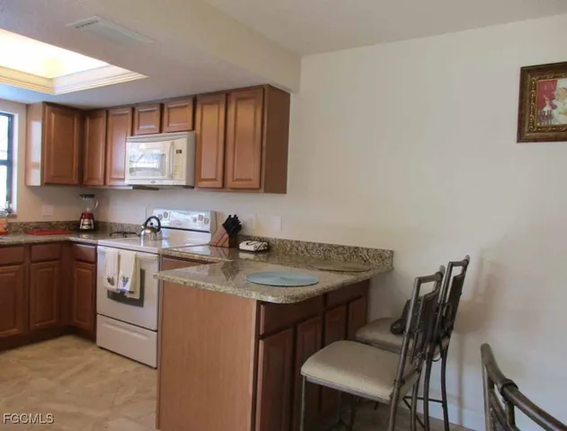 a kitchen with stainless steel appliances granite countertop a sink window and chairs