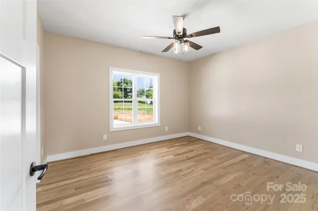 an empty room with wooden floor fan and windows