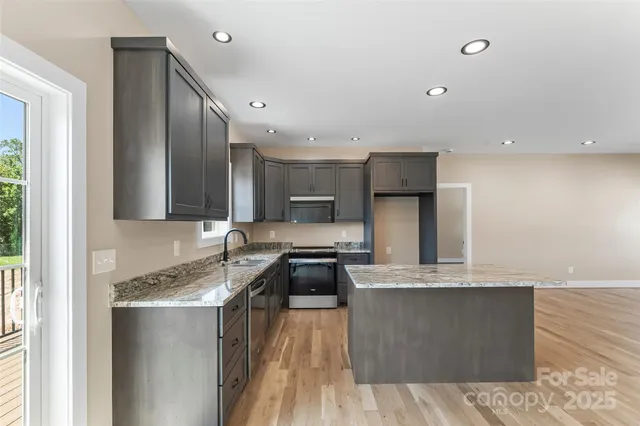 a kitchen with stainless steel appliances granite countertop a stove a sink and a refrigerator