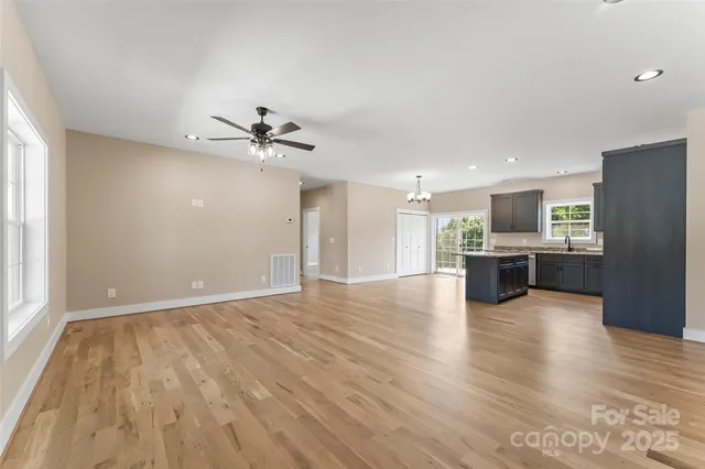 a view of an empty room with a kitchen and wooden floor