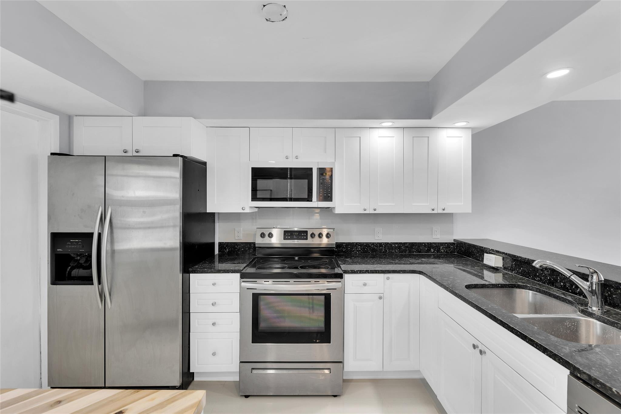3090 North Course Drive, Unit 609 Pompano Beach, FL 33069 - Photo 4 of 44 a kitchen with granite countertop a refrigerator stove and microwave