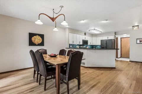 a kitchen with stainless steel appliances kitchen island granite countertop a table chairs and a refrigerator