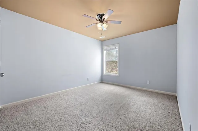 an empty room with a chandelier fan and windows