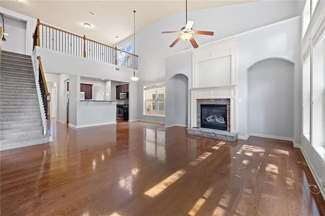 a view of an empty room with wooden floor fireplace and a window