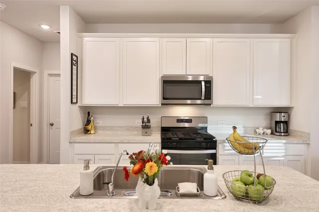 a kitchen with stainless steel appliances kitchen island granite countertop a sink a stove and a microwave