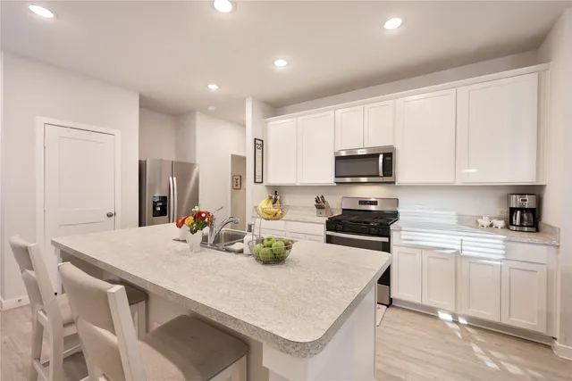 a kitchen with a stove a sink a microwave a dining table and chairs