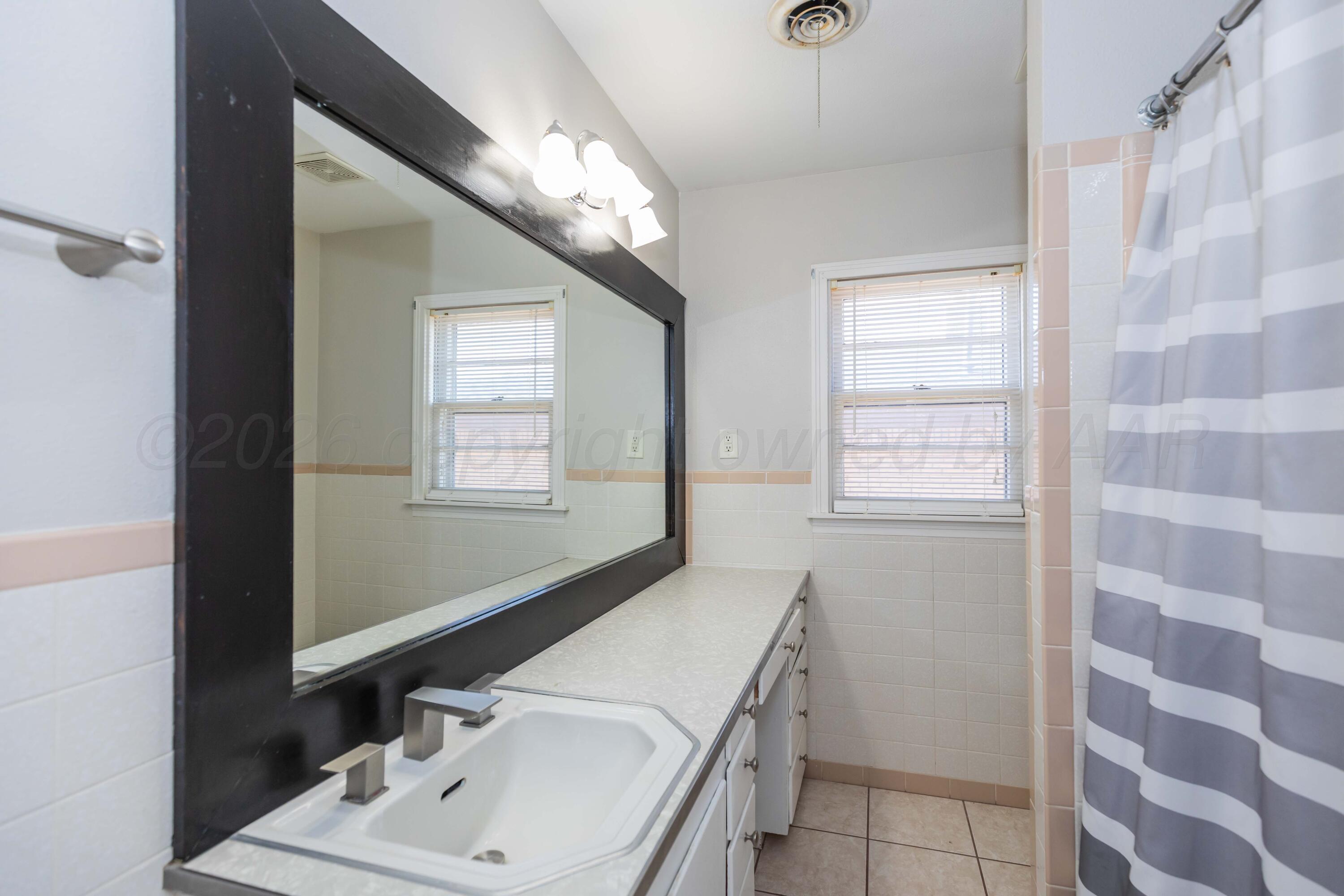1602 Mustang Street Amarillo, TX 79102 - Photo 16 of 36 a bathroom with a sink a vanity and a mirror
