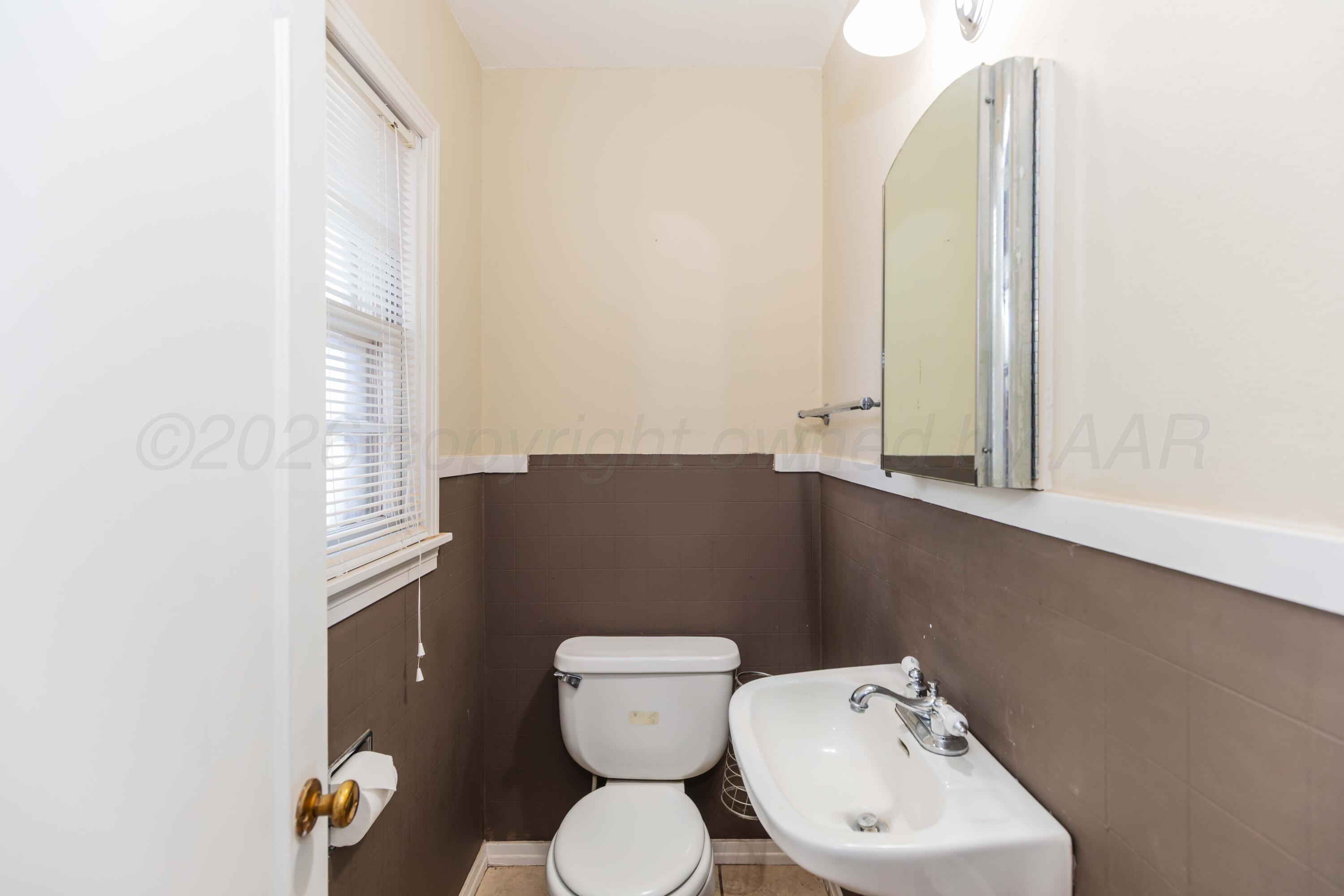1602 Mustang Street Amarillo, TX 79102 - Photo 28 of 36 a bathroom with a toilet sink and mirror
