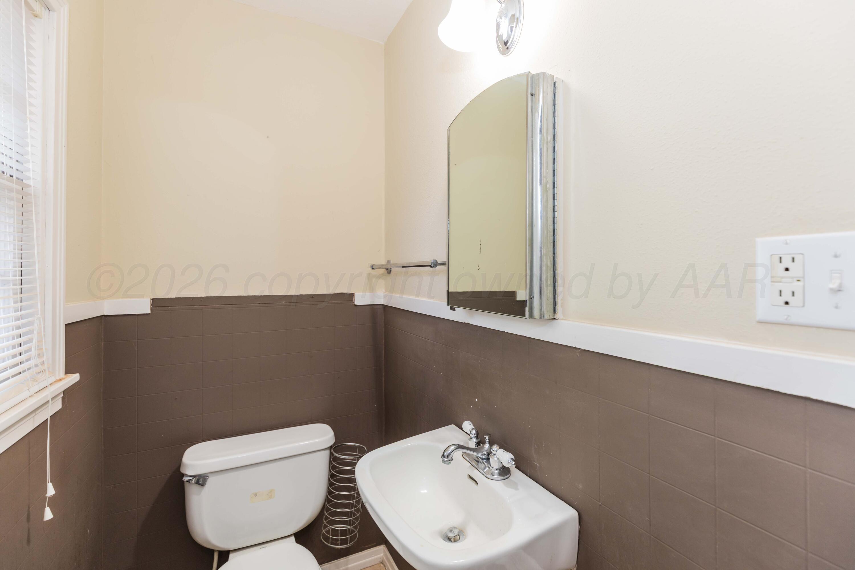 1602 Mustang Street Amarillo, TX 79102 - Photo 29 of 36 a bathroom with a toilet sink and mirror