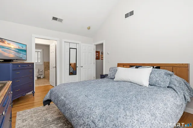 a large bed in a bedroom and a flat tv screen on dresser