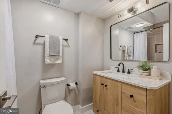 a bathroom with a granite countertop sink a toilet and mirror