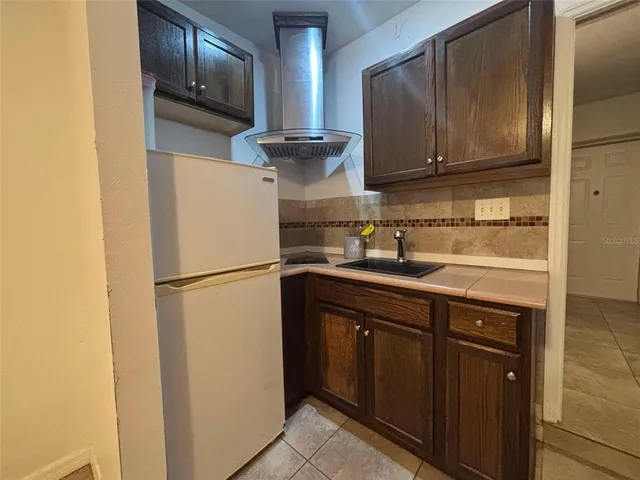 a kitchen with a sink a refrigerator and cabinets