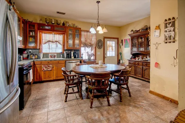 a dining area with stainless steel appliances granite countertop a stove a refrigerator a oven a dining table and chairs with the view of kitchen