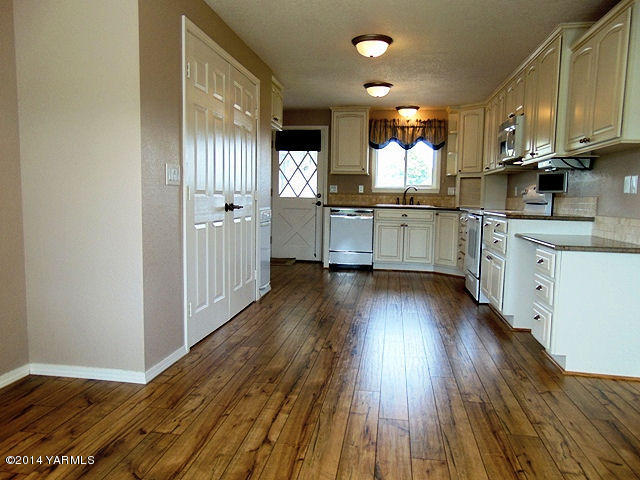 11301 Zier Road Yakima, WA 98908 - Photo 2 of 14 a kitchen with kitchen island granite countertop wooden floors and white cabinets
