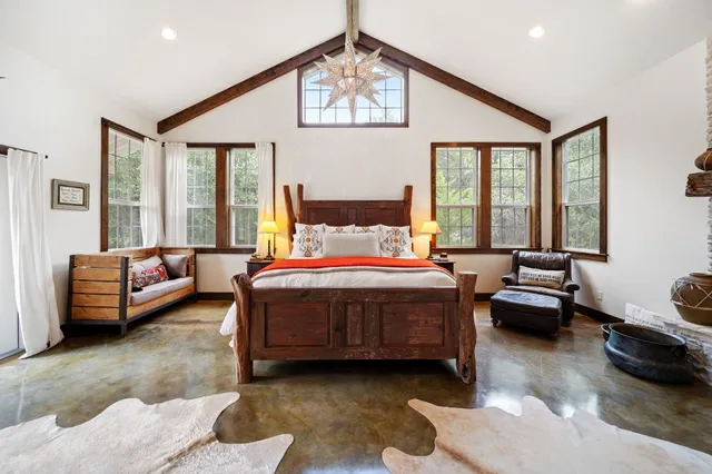 a spacious bedroom with a bed a couch and large window