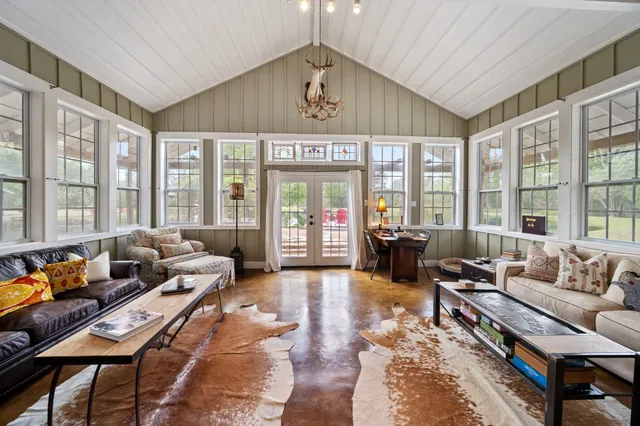 a dining room with wooden floor a chandelier a glass table and chairs