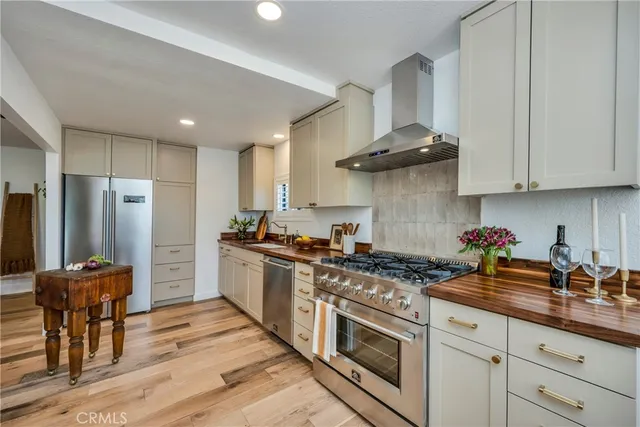a kitchen with stainless steel appliances granite countertop a stove a sink dishwasher and a refrigerator with wooden cabinets