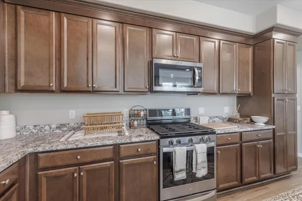 a kitchen with stainless steel appliances granite countertop white cabinets a stove top oven with wooden floor