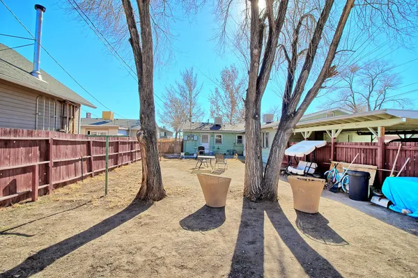 a view of a patio with couches and table and chairs under an umbrella with a small yard