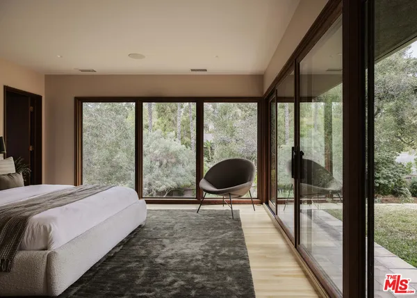 a bedroom with a bed lamp and large windows