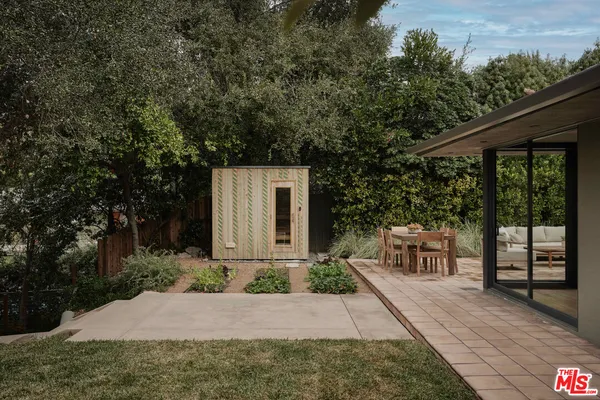 a view of a patio with table and chairs potted plants and large tree