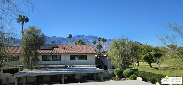 a view of a big house with a big yard and large tree
