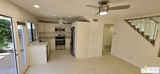 a view of kitchen with stainless steel appliances refrigerator stove and wooden floor