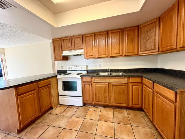 a kitchen with granite countertop a stove top oven sink and cabinets