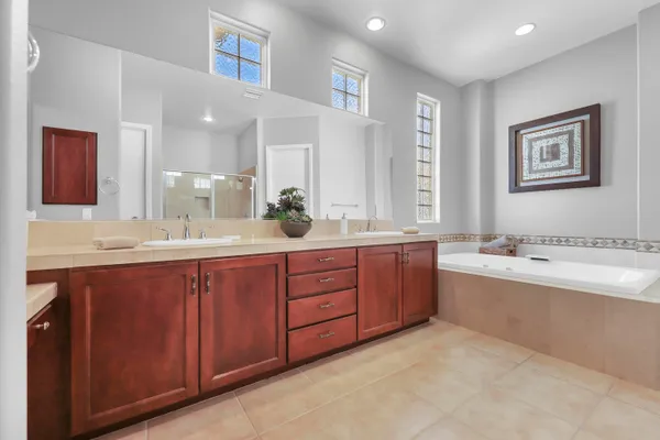 a bathroom with a granite countertop double vanity sink and mirror with bathtub