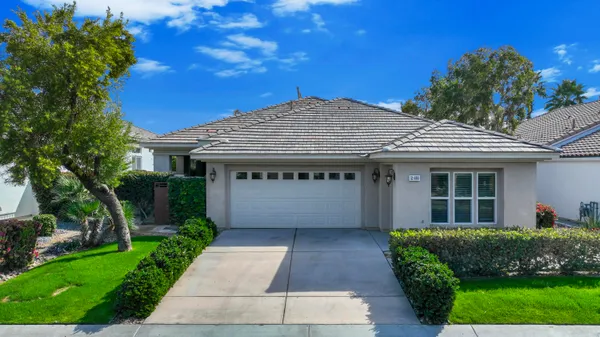 a front view of a house with a garden and plants