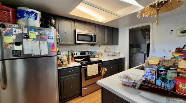 a kitchen with stainless steel appliances granite countertop a refrigerator a sink dishwasher and a stove with wooden floor