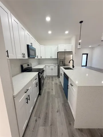 a large kitchen with stainless steel appliances sink a microwave and cabinets
