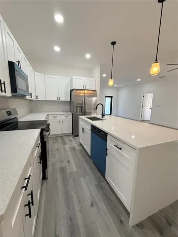 a kitchen with a sink a center island stainless steel appliances and cabinets