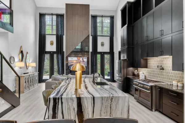 a kitchen with stainless steel appliances kitchen island granite countertop a stove a sink a refrigerator and a dining table with wooden floor
