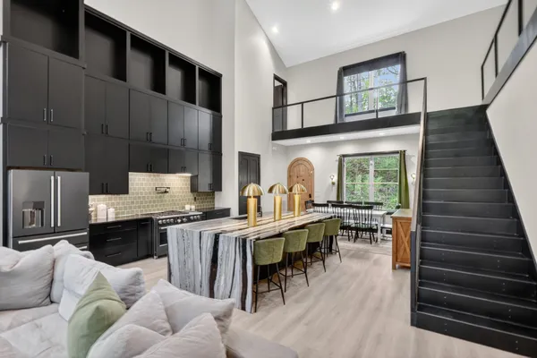 a kitchen with stainless steel appliances granite countertop a stove top oven a sink a dining table and chairs with wooden floor