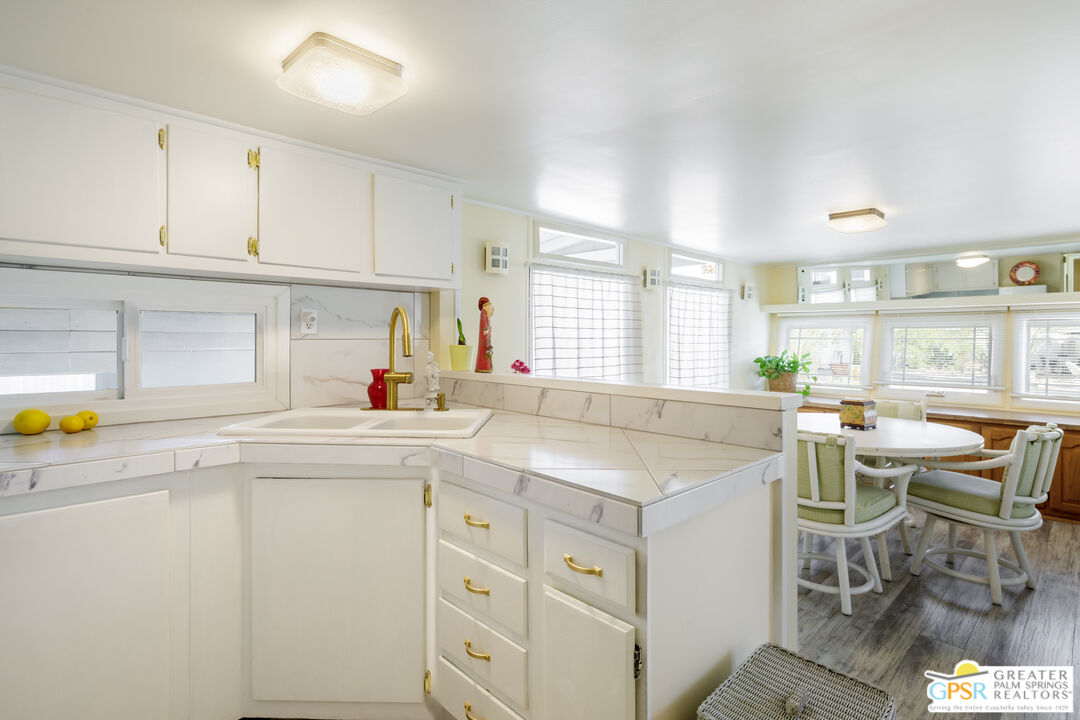 157 Caravan Street Palm Springs, CA 92264 - Photo 13 of 38 a kitchen with a sink a stove cabinets dining table and chairs