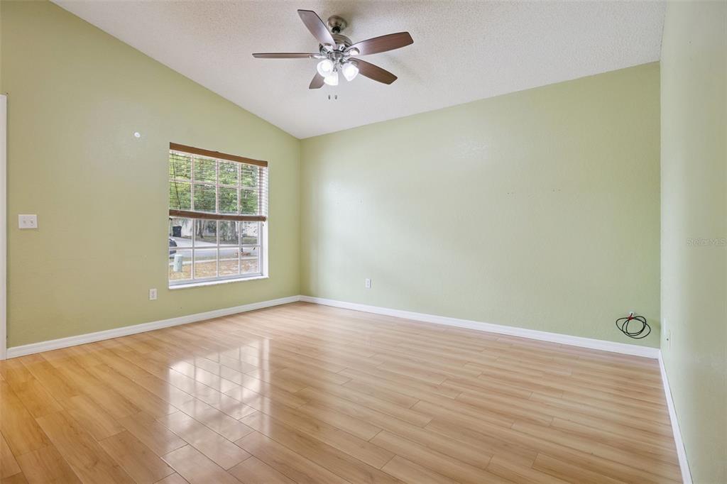 124 Diamond Ridge Boulevard Auburndale, FL 33823 - Photo 3 of 20 an empty room with wooden floor chandelier fan and windows