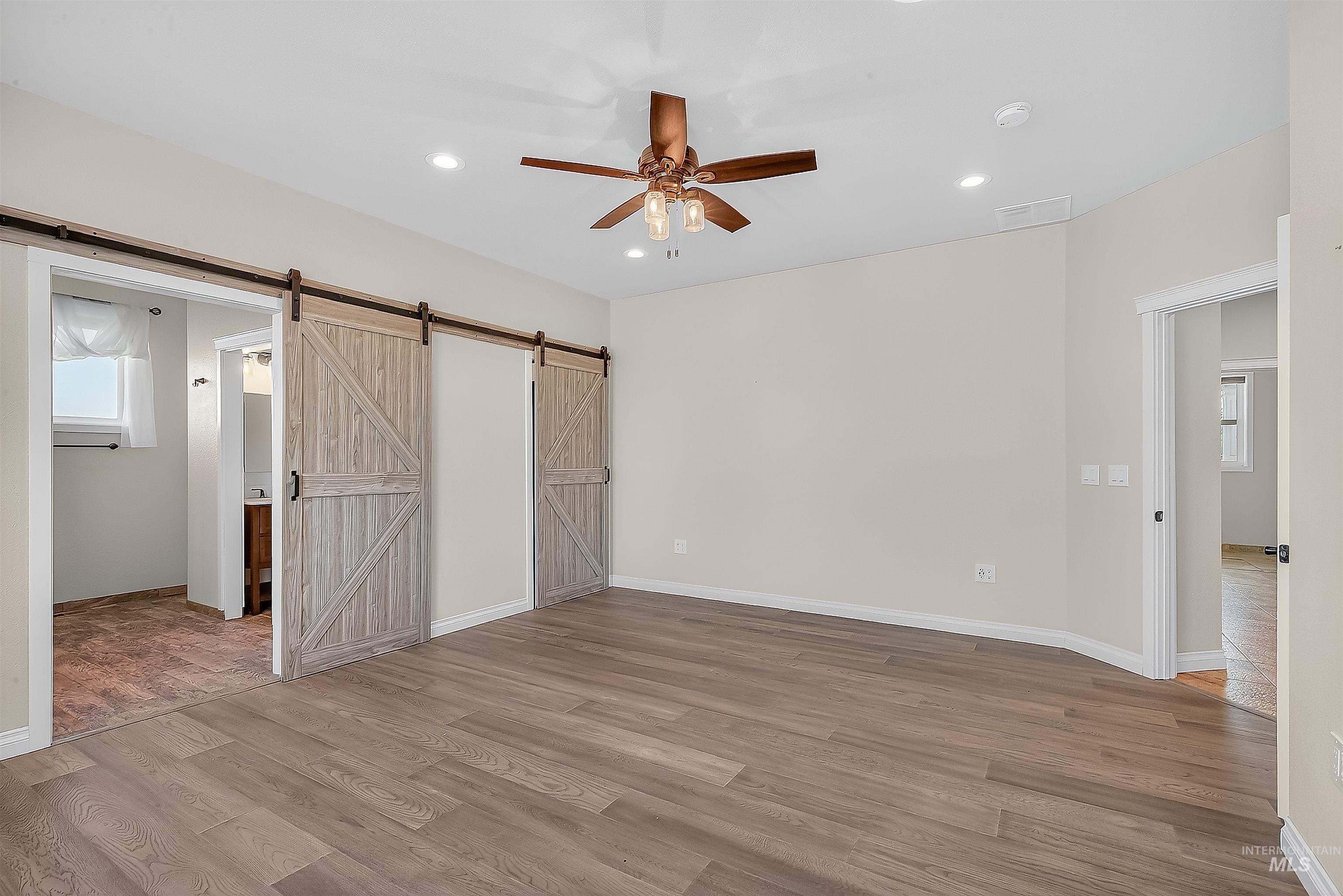 2233 Burrell Avenue Lewiston, ID 83501 - Photo 15 of 48 Unfurnished bedroom featuring multiple windows, light wood-style flooring, recessed lighting, a ceiling fan, and a barn door